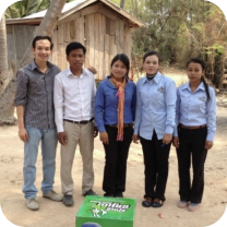 Five clean water experts stand in a rural Cambodia village with the Super Tunsai